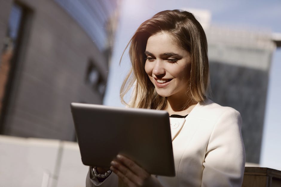 A woman joyfully using a digital tablet outdoors in the city during the day.